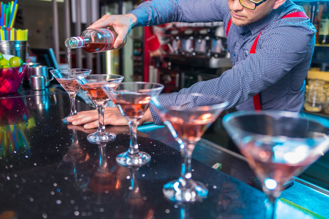 gallery-05 Bartender expertly pours cocktails with finesse at a vibrant indoor bar setting, creating a refreshing party atmosphere.